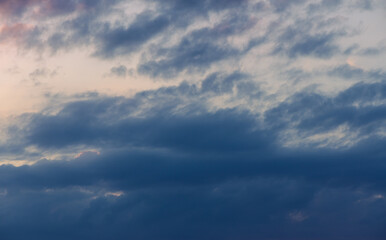 Dramatic cloud formations adorn the evening sky, blending soft hues of blue and gray near the horizon at dusk