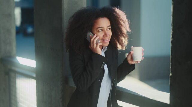 Successful confident businesswoman talking on mobile phone has working or personal conversation while has break at office centre Positive worker employee with cup of coffee using smartphone outdoors