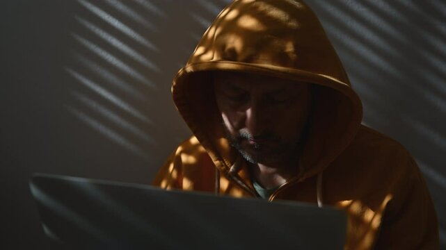Computer hacker wearing yellow hoodie using laptop, 4K