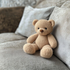 A crocheted mohair teddy bear sits adorably on a gray couch, enhancing the room's aesthetic. Greeting card design.