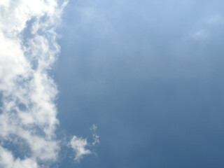 Obraz premium The sky has the light of the sun, the sky is blue, there are small and large clouds alternating and moving slowly, with the sunlight passing, creating a miraculous abstract shape, summer day.