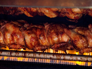 many chickens on the rotisserie Close-up shot of a steamy rotisserie machine window Grilled roasted whole chickens with tasty golden-yellow roasted skin on a turning spit in a row
