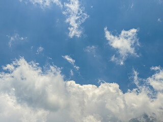 The sky has the light of the sun, the sky is blue, there are small and large clouds alternating and moving slowly, with the sunlight passing, creating a miraculous abstract shape, summer day.