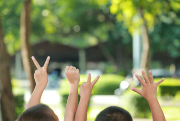 Children raising hands outdoors, each holding fingers in numbers 2025, symbolizing the year. The background shows greenery, creating a warm, playful atmosphere.