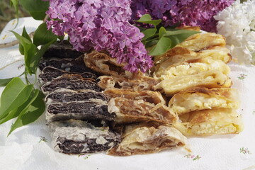 Nicely arranged piles of Hungarian retes (strudel) stuffed with poppy seeds, apple and cottage chesse. Decorated with lilac flower.