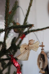 Handmade christmas tree decoration angel made of straw hanging on christmas tree branch.