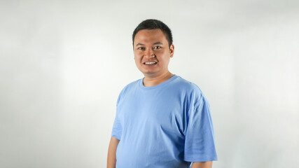 A young Indonesian man wearing a blue t-shirt with a smiling face facing forward