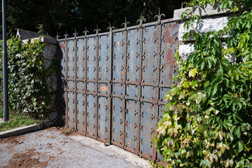 Fototapeta premium Rusted closed gate, made of metal, giving access to a private garden