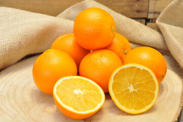 Oranges entières et coupées sur rondin et toile de jute 