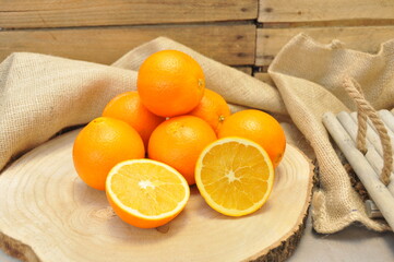 Oranges entières et coupées sur rondin et toile de jute 