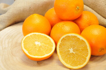 Oranges entières et coupées sur rondin et toile de jute 
