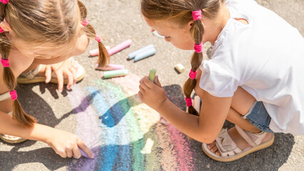 The child draws a a rainbow on the asphalt with chalk. Selective focus. Kids.