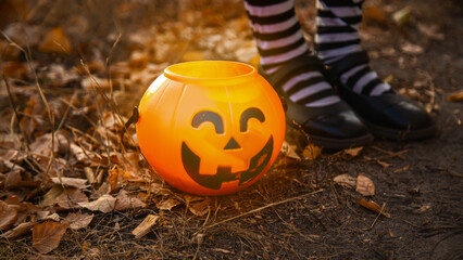 Close Up of unrecognizable child dressed carnival costume with basket shaped as Jack o lantern, ready for trick or treat holiday. Halloween background.
