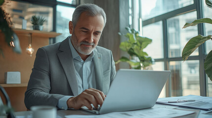 Fototapeta premium Focused Businessman Working on Laptop in Modern Office