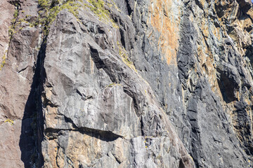 Sunlight illuminating a large rock face covered in vegetation
