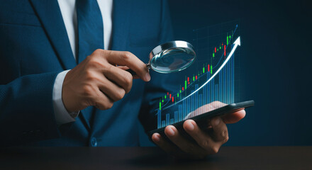 Businessman holding a magnifying glass analyze upward trend stock chart with smartphone.