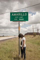 Young woman standing under amarillo city limits sign
