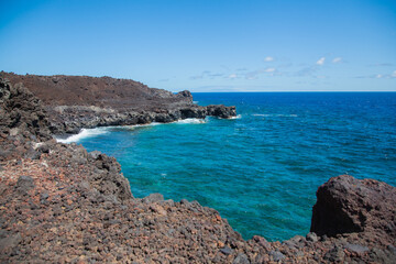 Turquoise water crashing volcanic lava rocks coastline