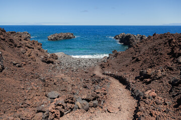 Volcanic trail leading to cove with turquoise water