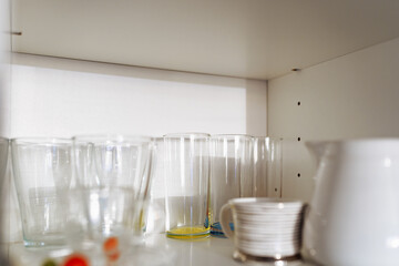 Clean dishes and tableware on white shelf