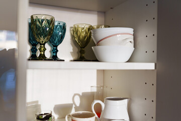 Clean dishes and tableware on white shelf