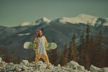  A girl with a snowboard in her hands against the backdrop of snowy mountains