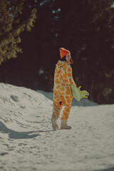  A girl with a snowboard in her hands against the backdrop of snowy mountains