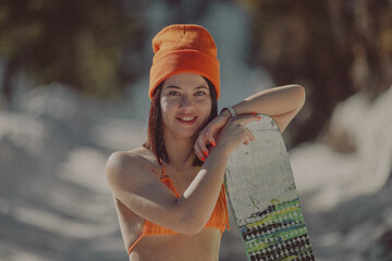  A girl with a snowboard in her hands against the backdrop of snowy mountains