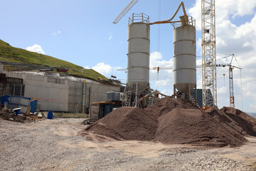 Obraz premium crane stands idle at a construction site with towering silos and piles of dirt during a strike with no workers present
