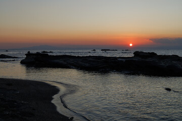 キレイな夕日と波打ち際岩場とともに
