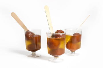 Indian dessert Gulab Jamun in glass cups with wooden spoon on white background