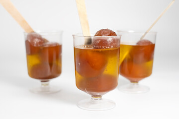 Indian dessert Gulab Jamun in glass cups with wooden spoon on white background