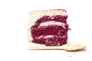 Slice of delicious red velvet cake with wooden spoon on white background
