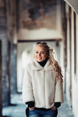 Smiling young woman walking under archway in europe