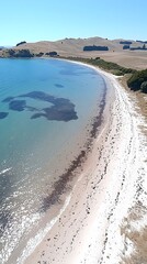 A serene coastal landscape showcasing a stretch of sandy beach along a calm blue ocean under a clear sky, creating a peaceful and inviting atmosphere.
