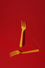 Yellow Plastic forks on red background with shadow. Minimalism. Creative layout. Food concept