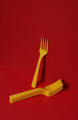 Yellow Plastic forks on red background with shadow. Minimalism. Creative layout. Food concept