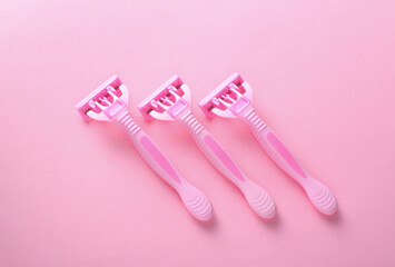 Pink plastic razors on a pink background. Top view