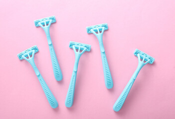 Blue disposable razors on pink background