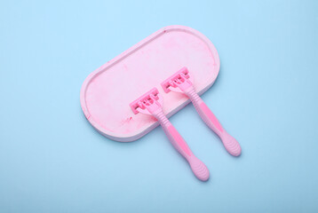 Blue disposable razors with plaster tray, blue background.