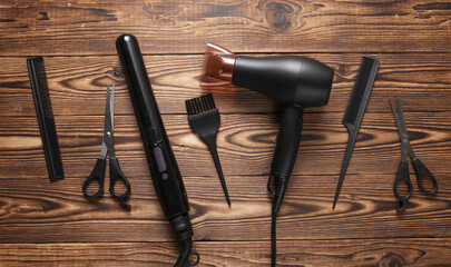 Flat lay hairdressing tools and accessories for hair styling on wooden background. Top view
