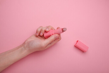 Hand Holding Lipstick On Pink Background