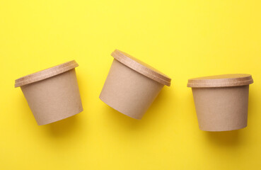 Eco cardboard round food boxes on yellow background. Top view