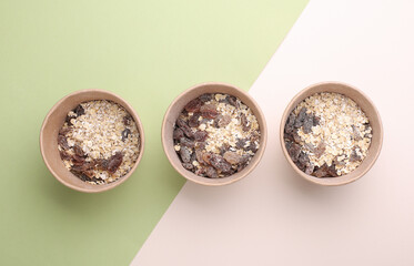 Oatmeal with raisins in a disposable craft boxes on beige green background. Healthy fast food. Top view