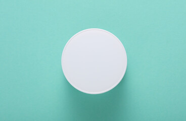 White cream jar on mint green background. Top view