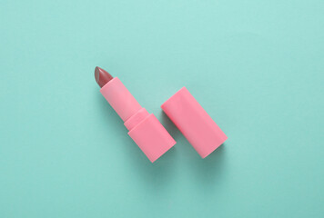 Tube of pink lipstick on mint green background