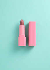 Tube of pink lipstick on mint green background
