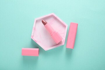 Tube of pink lipstick in tray on mint green background. Minimalism. beauty still life