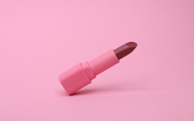 Pink lipstick tube floating on pink background