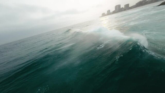 Drone flight over the atmospheric coastline of Rio de Janeiro, where the sun peeks through the clouds, casting a soft, diffused light over the Atlantic Ocean.